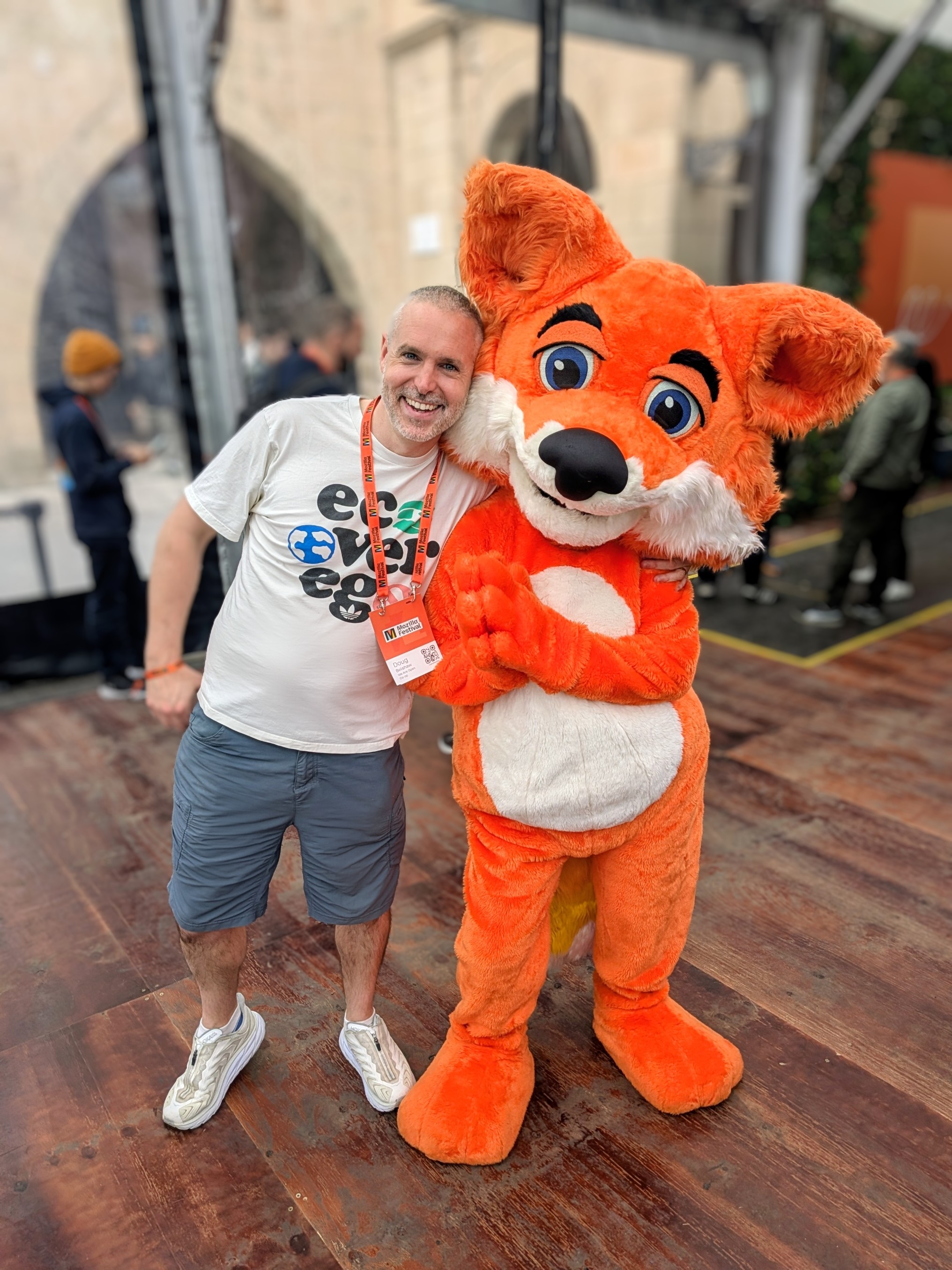 Doug Belshaw at MozFest Barcelona 2025, cheerfully hugging the Mozilla FuzzyFox mascot